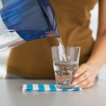Closeup On Housewife Pouring Water Into Glass From Water Filter